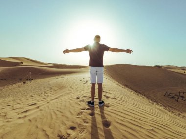 Genç güzel adam Dubai çölkum tepeleri boyunca yürüyor