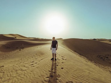 Genç güzel adam Dubai çölkum tepeleri boyunca yürüyor