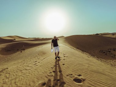 Genç güzel adam Dubai çölkum tepeleri boyunca yürüyor