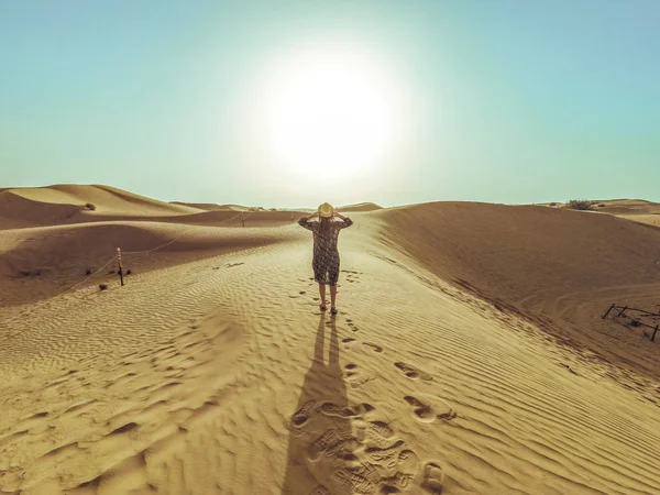 Joven mujer hermosa en un vestido largo pasea por las dunas de arena del desierto de Dubai — Foto de Stock