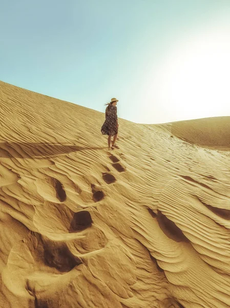 Joven mujer hermosa en un vestido largo pasea por las dunas de arena del desierto de Dubai — Foto de Stock