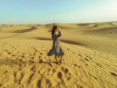 Uzun elbiseli ve güneş ışığı ile Dubai çölün ortasında bir şapka ile genç güzel kadın