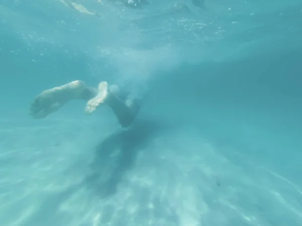 Молодий чоловік плаває у синьому глибоководному морі. Підводна стрілянина — стокове фото