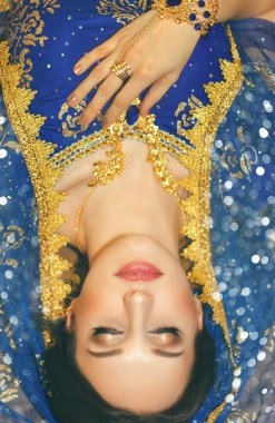 Hint kadın kostümü. Mavi Hint elbisesi giymiş genç güzel bir kadın çok renkli kahverengi arka planda yakın çekim yapıyor..