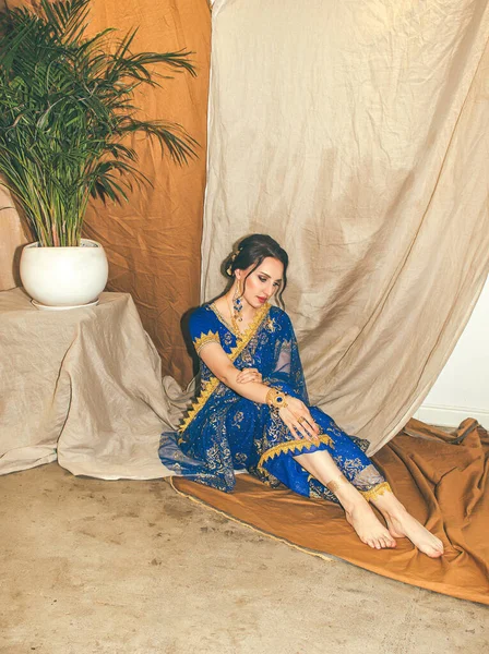 Hint kadın kostümü. Mavi Hint elbisesi giymiş genç güzel bir kadın çok renkli kahverengi arka planda yakın çekim yapıyor..