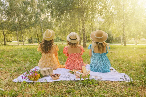 Three pretty womans on the picnic in the park at summertime season.