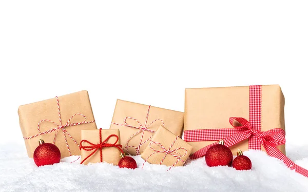 Weihnachtsgeschenke in braunes Papier gewickelt mit roter Schleife und Schnee isoliert auf weißem Hintergrund — Stockfoto