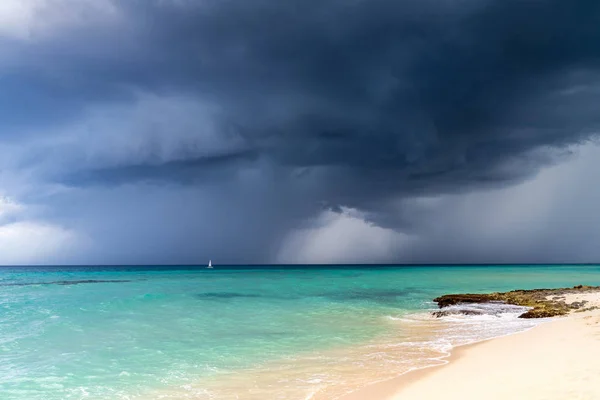 Veduta drammatica delle nuvole di tempesta grigio scuro contro l'acqua turchese blu del mare dei Caraibi e una spiaggia di sabbia bianca — Foto Stock