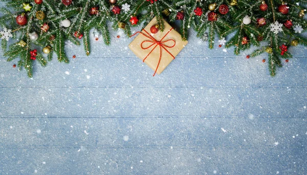 Tannenzweige und Weihnachtsschmuck mit Geschenk auf schneeblauer Holzplanke — Stockfoto