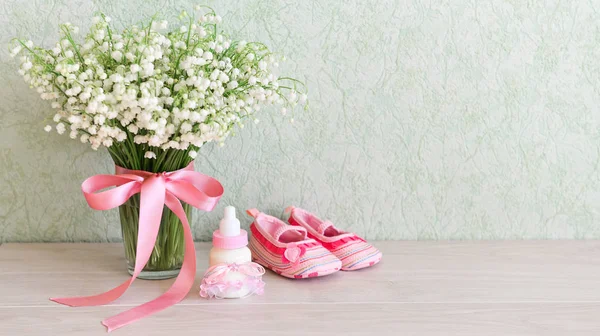 Дитяче взуття на столі біля букета квітів. Для дитячого душу святкуйте. для тематичного декору на день народження — стокове фото