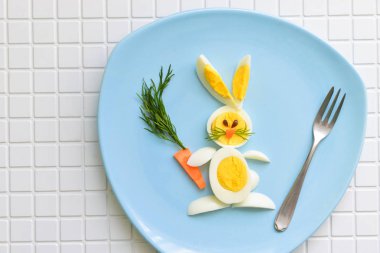 Neşeli çocuk kahvaltı çocuk için. tavşan yumurta ve havuç. mavi plaka üzerinde yatıyor