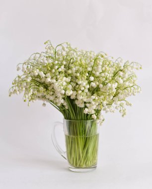 vahşi lily-ve--Vadisi buket kupa su ile izole beyaz arka plan üzerinde duruyor