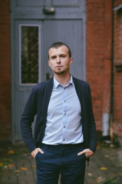 Genç adam tuğla ev cadde üzerinde duruyor. Mimari, açık havada doğa