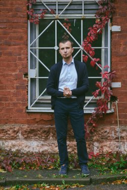 Genç adam tuğla ev cadde üzerinde duruyor. Mimari, açık havada doğa