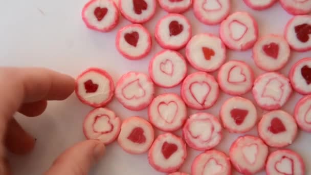 手に触れる砂糖キャンディ ロリポップ ハート フォーカスをフローティング トップ ビューのイメージの中の赤とピンク色の丸いフォルムの — ストック動画