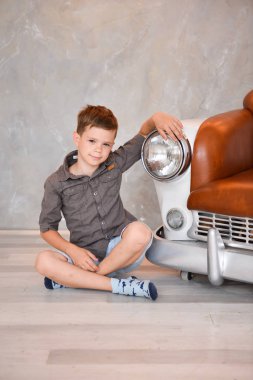 Çocuk iç stüdyo retro bir araba şeklinde bir sandalyeye oturmuş. yaratıcı vintage mobilya