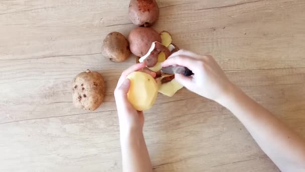 Χέρια ξεφλούδισμα πατάτας με ένα μαχαίρι. Το top view. συνταγή πιάτων, οικιακού βίντεο — Αρχείο Βίντεο