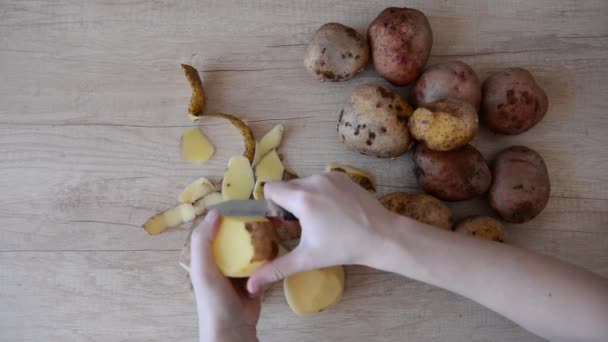 Mãos descascando batatas com uma faca. Vista superior. pratos de receita, vídeo caseiro — Vídeo de Stock