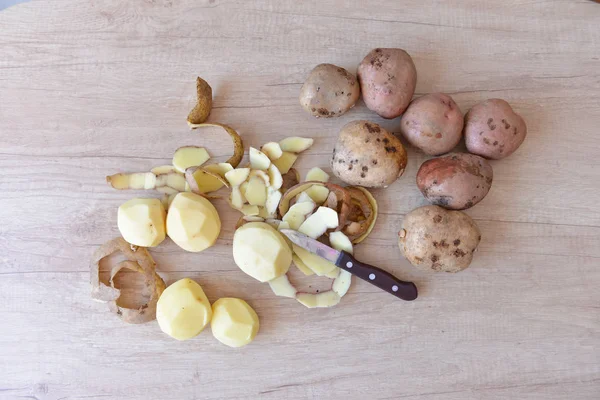 raw potatoes in the process of cleaning lies on a table next to a knife. cleaning, peel. clean potatoes