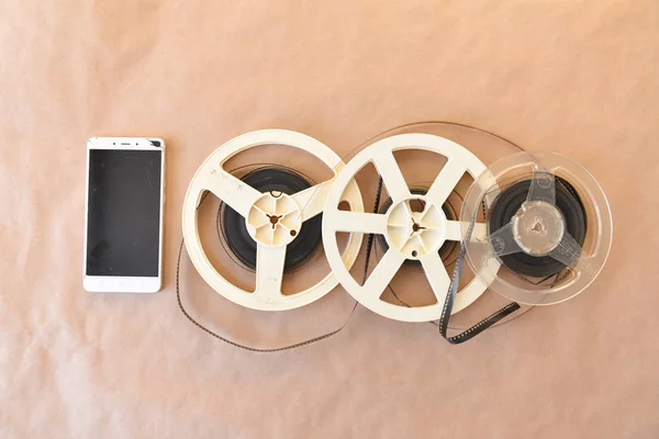 Old vintage cinematic reels with a video film lie on the background of the Kraft surface. Top view. broken phone — Stock Photo, Image