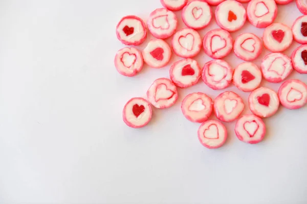 Runde Bonbons mit Herzmuster liegen als Textur und Eckrahmen auf einem Papierhintergrund — Stockfoto