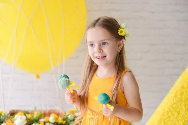 Grattis på födelsedagen flicka i en studio en festlig inredning firar en födelsedag, godis inredning chokladkaka i gul grön färg — Stockfoto