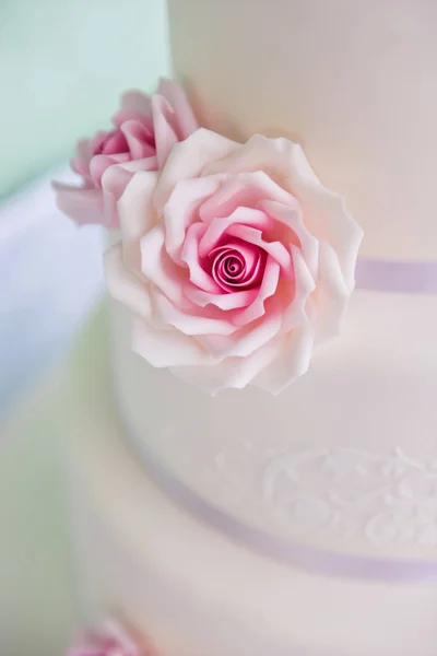 Torta de boda de tres niveles con rosas rosadas hechas de soportes de masilla sobre la mesa un fondo delicado. cartas novia y novio —  Fotos de Stock