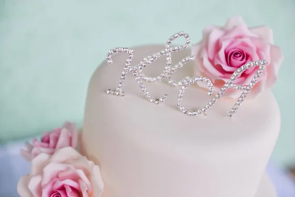 Torta de boda de tres niveles con rosas rosadas hechas de soportes de masilla sobre la mesa un fondo delicado. cartas novia y novio —  Fotos de Stock