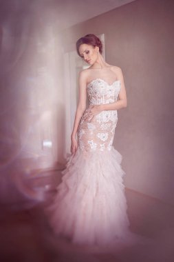 Hassasiyet moda gelin. Genç güzel kız mükemmel cilt ve makyaj, rhinestones ve dantel, saçında çiçekler ile bir gelinlik modeli. Yumuşak odak, tonlama