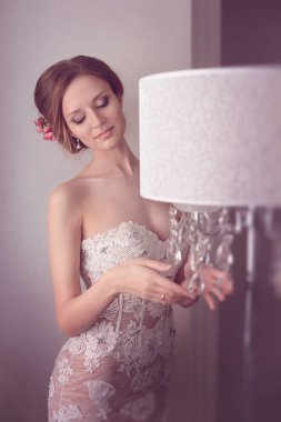 Hassasiyet moda gelin. Genç güzel kız mükemmel cilt ve makyaj, rhinestones ve dantel, saçında çiçekler ile bir gelinlik modeli. Yumuşak odak, tonlama
