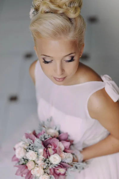 Porträt eines eleganten Modelmädchens Braut Blondine in einem zarten Kleid mit einem Brautstrauß aus Rosen und Orchideen drinnen — Stockfoto