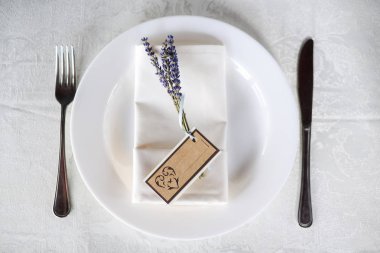 Düğün masa bir tabak, kaşık, çatal ve Lila Konuklar adı için bir işaret ile bir delikanlı ile ayarlama