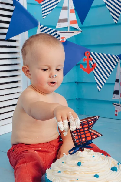 Dekorasyon çocuklar doğum günü için pasta bir deniz deniz tarzda şut. stilize doğum günü gemi fotoğraf çekimi. Neşeli çocuk yiyor ve bir pasta elleriyle ilk tatilde kırmak.
