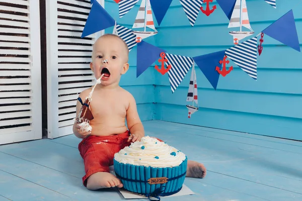 Dekorasyon çocuklar doğum günü için pasta bir deniz deniz tarzda şut. stilize doğum günü gemi fotoğraf çekimi. Neşeli çocuk yiyor ve bir pasta elleriyle ilk tatilde kırmak.