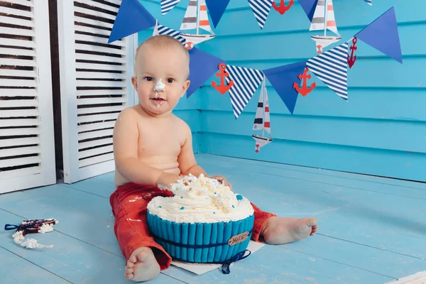 Dekorasyon çocuklar doğum günü için pasta bir deniz deniz tarzda şut. stilize doğum günü gemi fotoğraf çekimi. Neşeli çocuk yiyor ve bir pasta elleriyle ilk tatilde kırmak.