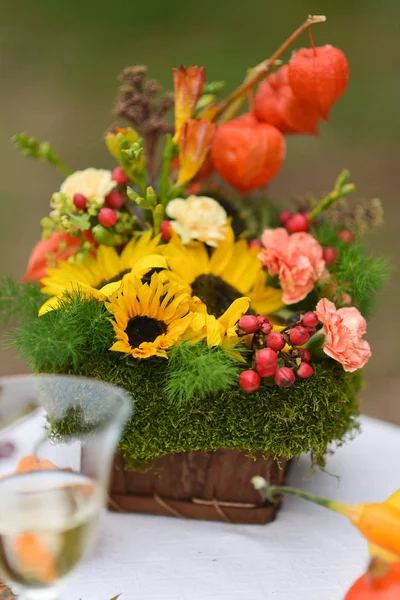 Autumn floral bouquet with sunflowers and physalis vase for Halloween. Table setting and floral decor for a rustic wedding