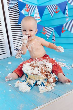 Dekorasyon çocuklar doğum günü için pasta bir deniz deniz tarzda şut. stilize doğum günü gemi fotoğraf çekimi. Neşeli çocuk yiyor ve bir pasta elleriyle ilk tatilde kırmak.