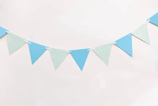 Festliche Dekoration für Kinderurlaub, um die Torte zu zertrümmern, Geburtstag, Baby-Shower. blaue dreieckige Flaggen an weißer Wand — Stockfoto