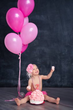 temalı doğum günü için eğlenceli bir duygusal kız sarışın siyah bir zemin üzerine pembe renkli pasta şut. stilize Fotoğraf oturumu geleneği ile tatlı dekor ve balon