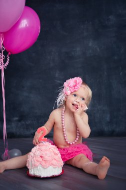 temalı doğum günü için eğlenceli bir duygusal kız sarışın siyah bir zemin üzerine pembe renkli pasta şut. stilize Fotoğraf oturumu geleneği ile tatlı dekor ve balon