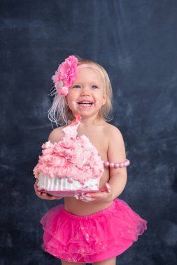 temalı doğum günü için eğlenceli bir duygusal kız sarışın siyah bir zemin üzerine pembe renkli pasta şut. stilize Fotoğraf oturumu geleneği ile tatlı dekor ve balon