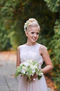 güzel zarif sarışın gelin alışılmadık bir sonbahar buket ile yolda bir parkta duruyor