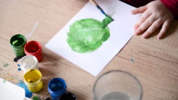 子供の手は、紙の上の木製のテーブルの表面に水彩画を描きます。子供の創造性、家族の趣味の水彩画の絵画 — ストック動画