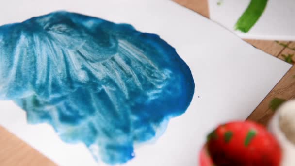 儿童绘制水彩画特写蓝色圆圈和黑色条纹。蓝色太阳绘画在表现主义风格的孩子的孩子在白纸上用画笔。创意和艺术 — 图库视频影像