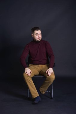 bir sakallı bir izole koyu arka plan üzerinde stüdyoda bir bordo kazaklı rahat kıyafetler teşkil etmektedir