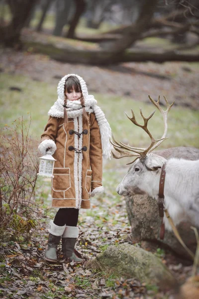 Teenager girl with reindeer walks with a park in spring in the forest and feeds him — Stock Photo, Image