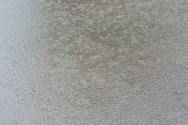 La textura de la lluvia ligera en la superficie del charco, textura ondulaciones de agua de gris, gotas de lluvia naturales círculos en el agua — Foto de Stock