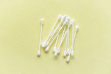 Sarı arka planda plastik tabanda beyaz pamuklu kulak çubukları