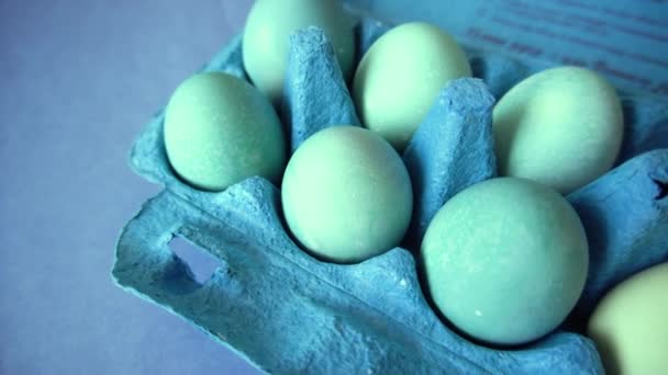 木製のテーブル、モノクロの上にエコカートン包装でイースターの休日に描かれた自然な有機青い家禽の卵 — ストック動画