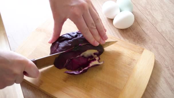 As mãos femininas cortam com uma faca um repolho vermelho em uma mesa de madeira. Prepare um corante natural para ovos de Páscoa azuis — Vídeo de Stock